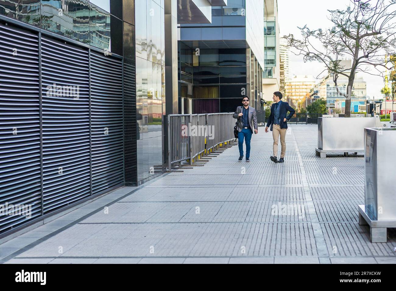 Two colleagues walking on the street while talking about the past ...