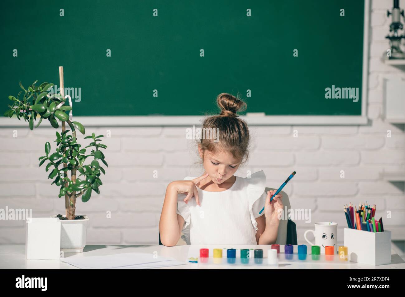 Little girls drawing a colorful pictures with pencil crayons in school ...