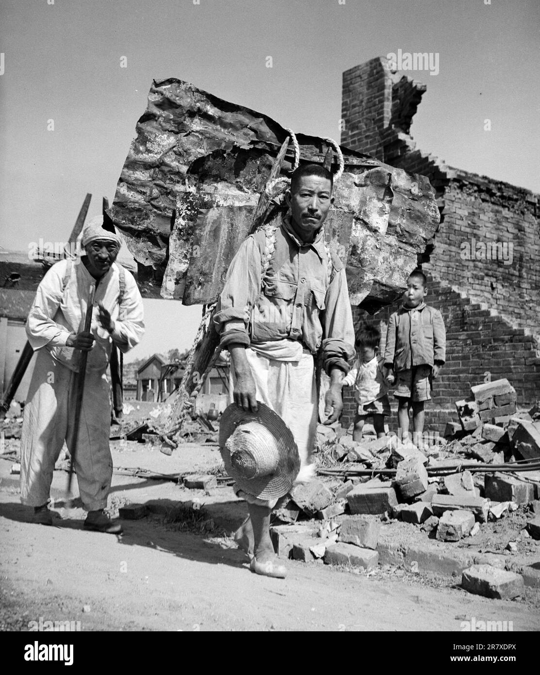 Civilians recovering building materials from the ruins in Inchon during the Korean War. Stock Photo