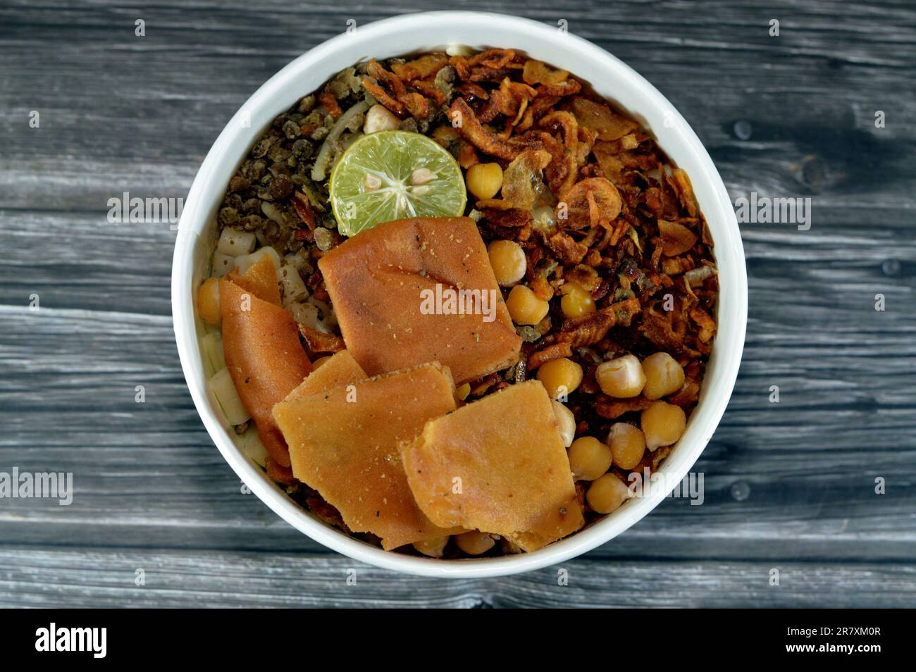 Egyptian cuisine of Koshary, a popular street food made of rice, macaroni, spaghetti and lentils mixed together topped with pieces of toast bread, gar Stock Photo