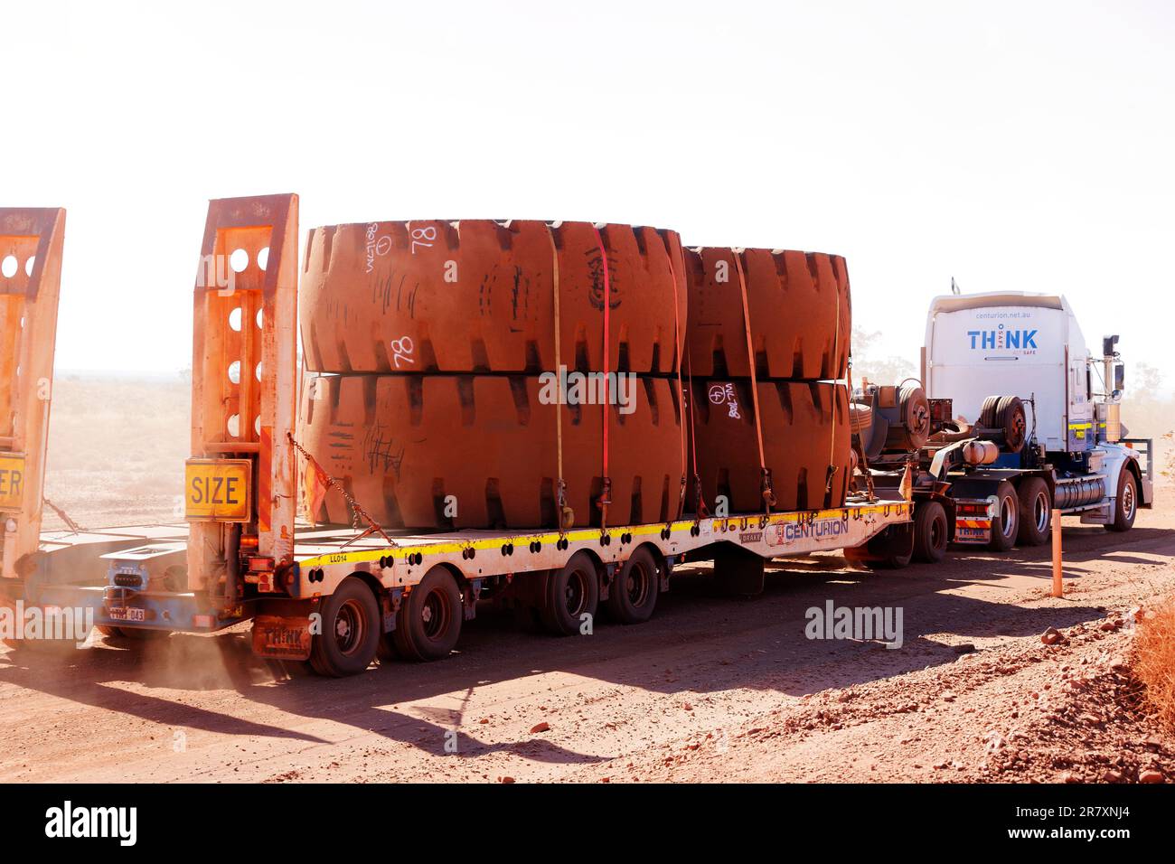 Giant wheels being transported by truck on Australian outback road, Pilbara, Western Australia