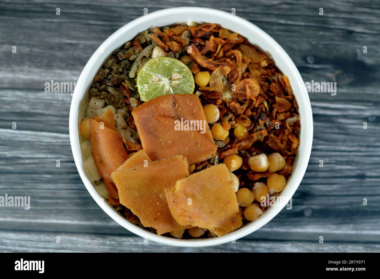 Egyptian cuisine of Koshary, a popular street food made of rice, macaroni, spaghetti and lentils mixed together topped with pieces of toast bread, gar Stock Photo
