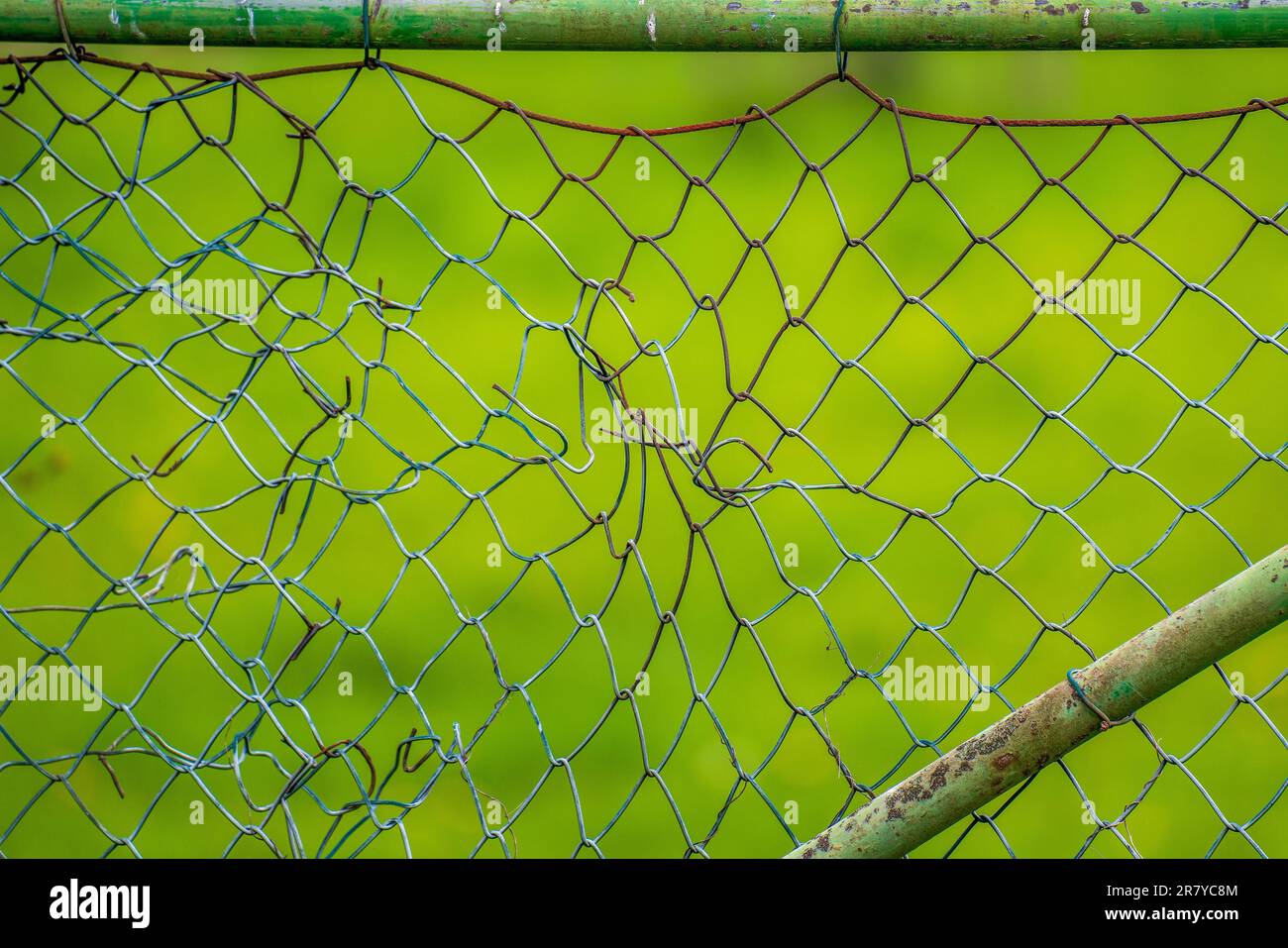 Broken mesh wire fence in the field Stock Photo