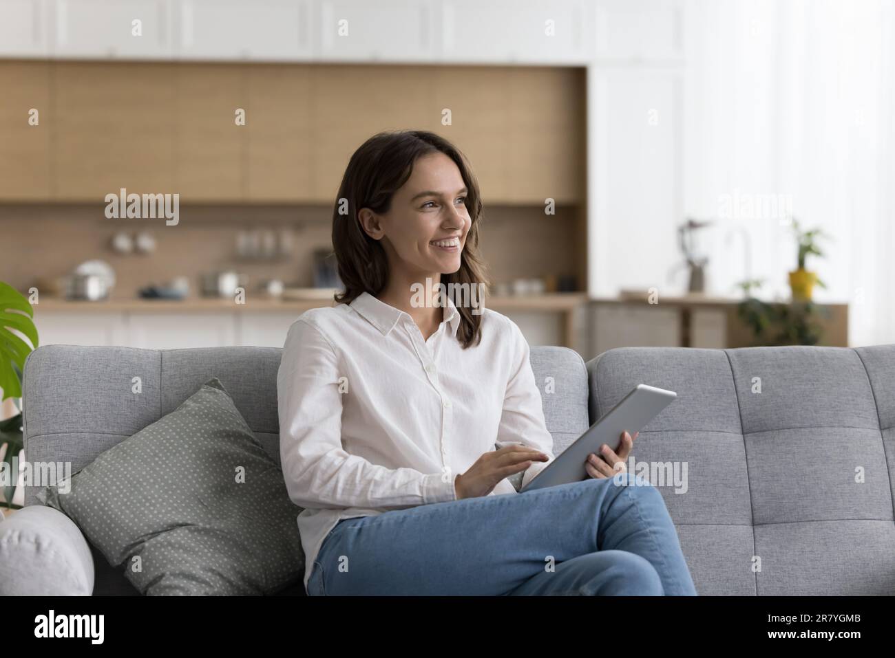 Pretty female relaxing on couch with modern digital tablet Stock Photo