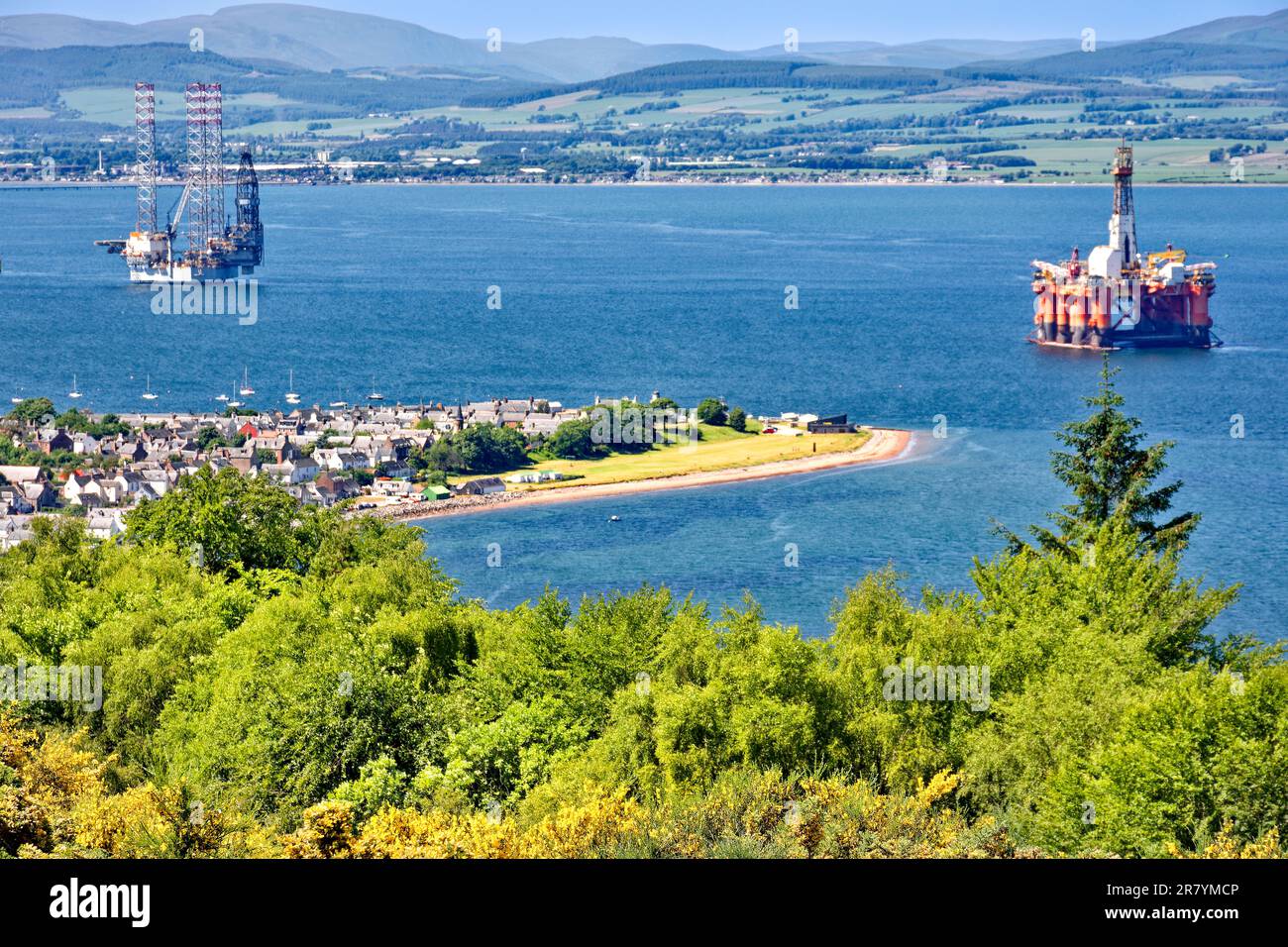 Cromarty Scotland Cromarty Firth a blue sky and a view over the town the houses and orange oil rig towards the hills in early summer Stock Photo