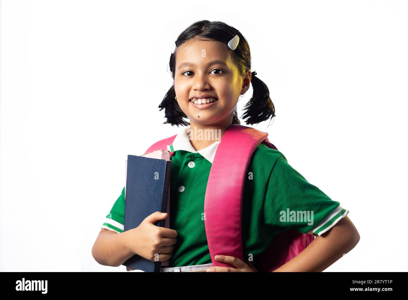 A pretty beautiful Indian schoolgirl child with books and school bag ...