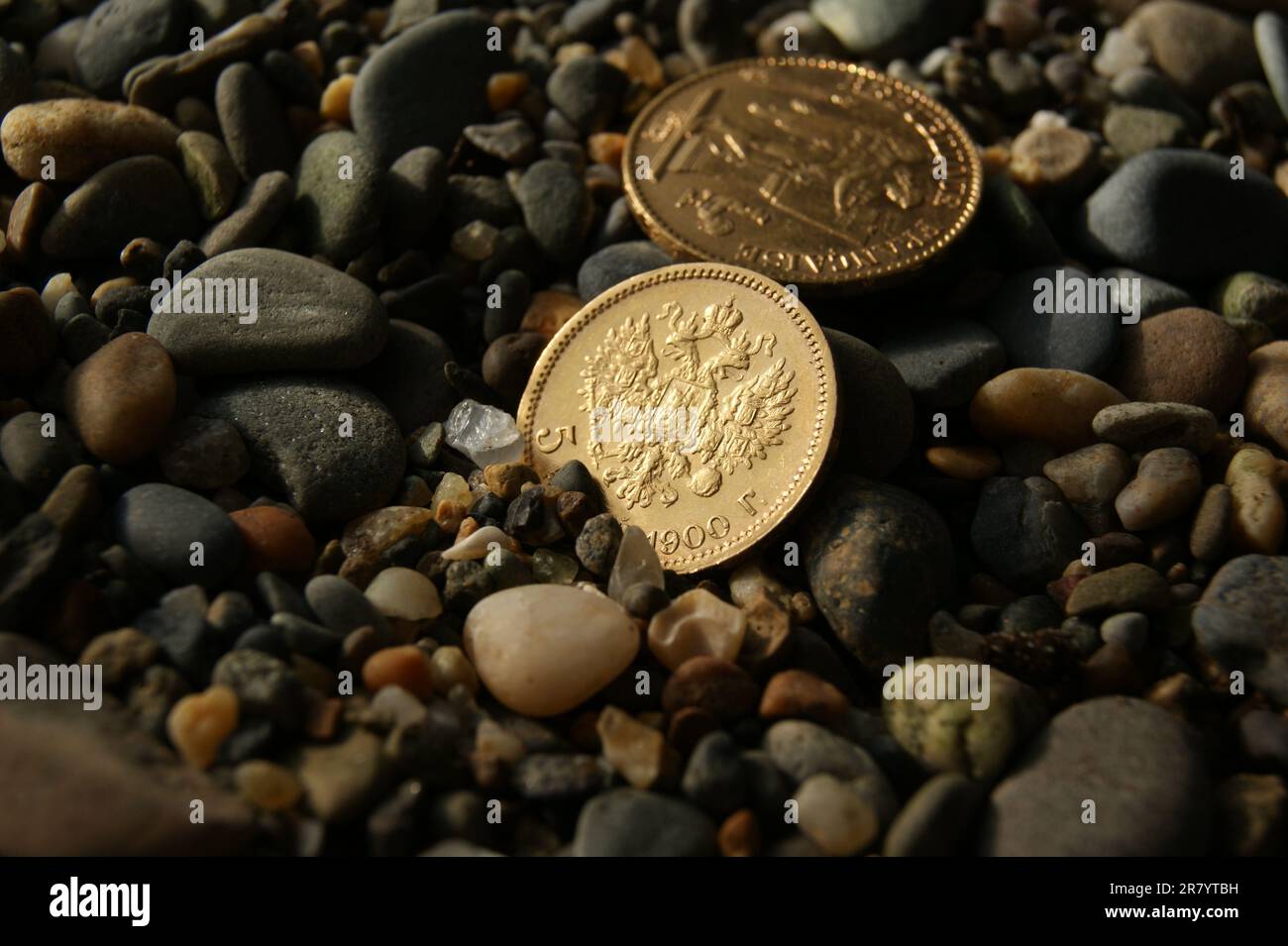 Russian and French old gold coins on stones. 5 ruble and 20 francs. Stock Photo