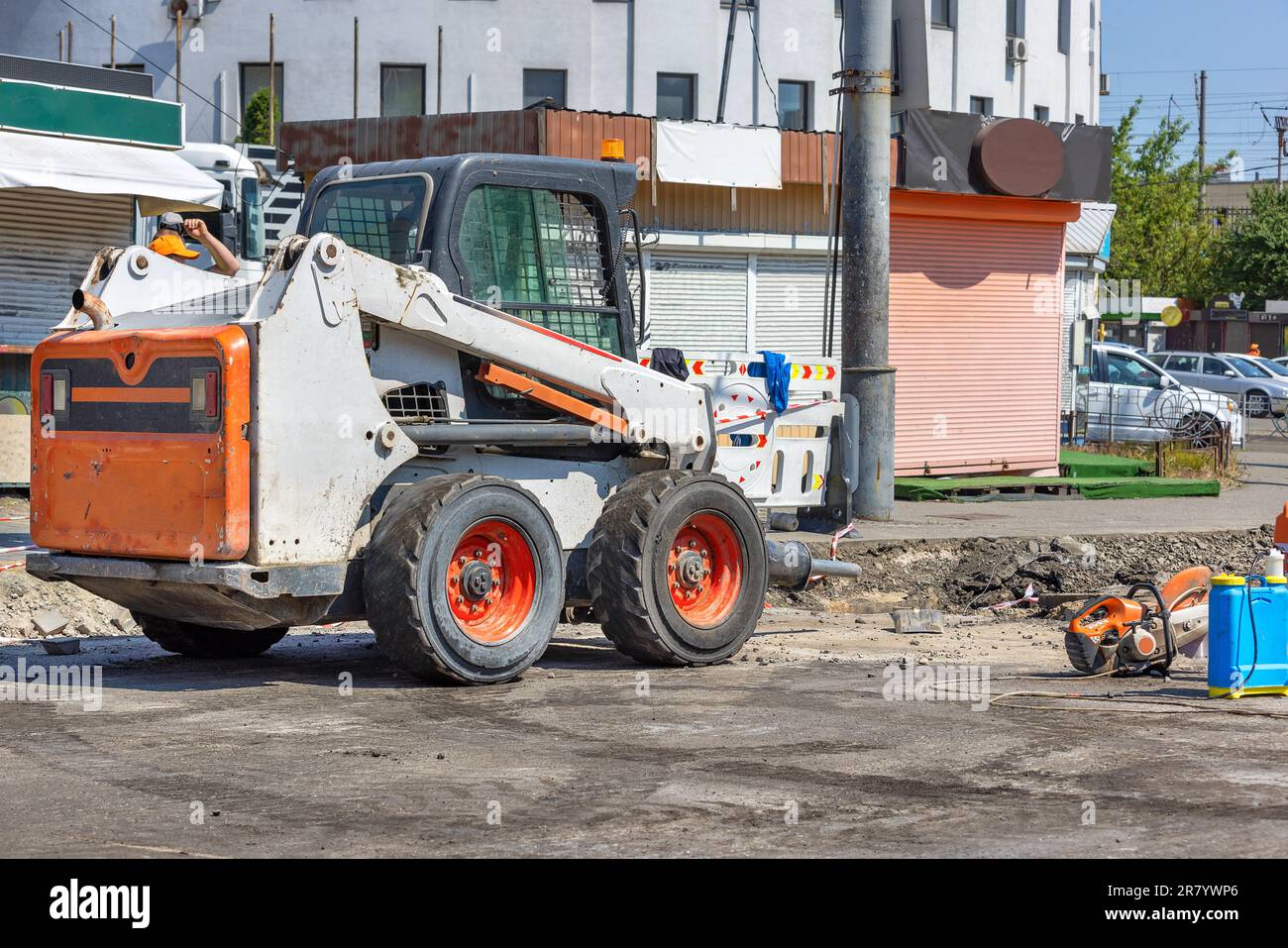 On the repaired section of the carriageway, compact and powerful construction equipment is parked along with a petrole cutter. Copy space. Stock Photo