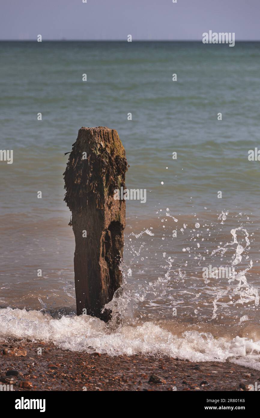 The sea splashing against a wooden sea defence at Worthing beach, UK Stock Photo
