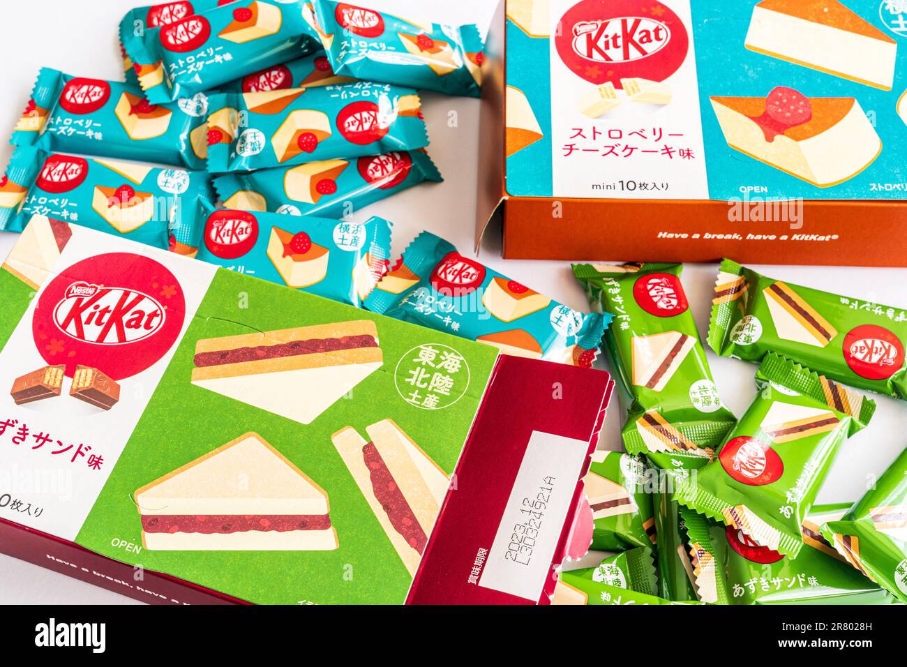 Two box packets of Red Bean and Strawberry cheesecake Japanese kitkats with several two finger wrapped mini bars arranged around them. Stock Photo