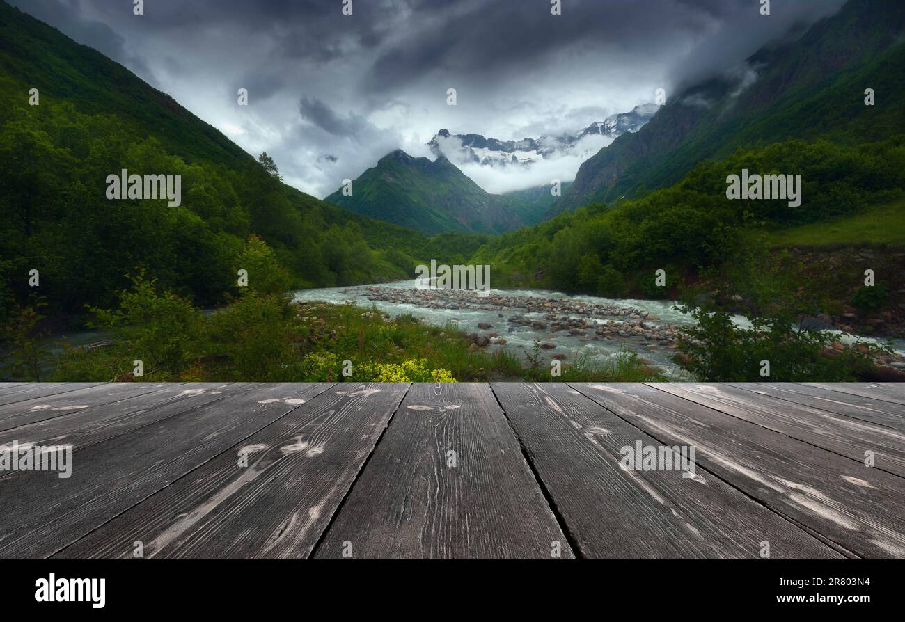 Fast mountain river flowing with empty wooden batten bridge. Natural ...