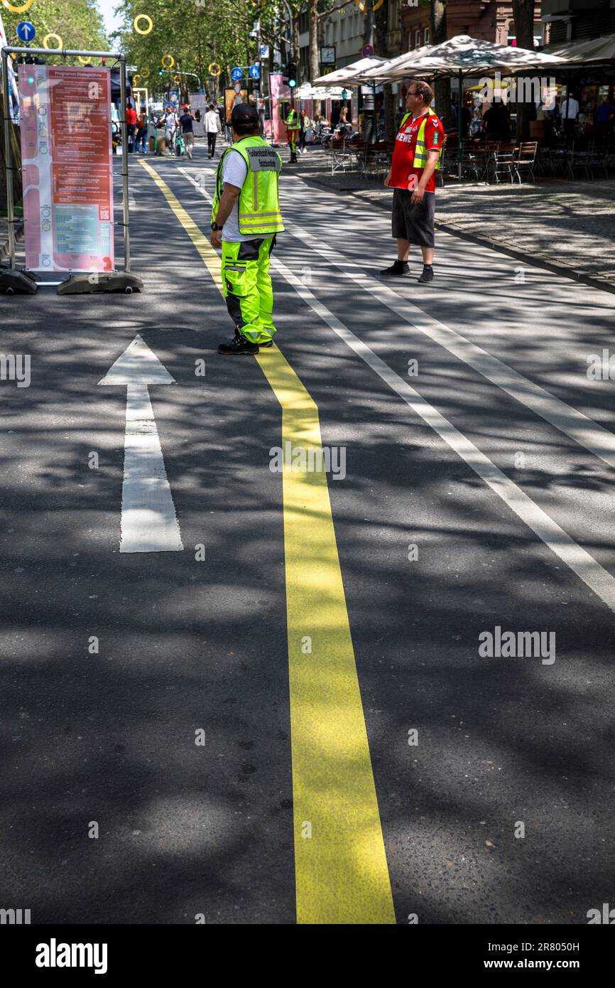 a man in yellow protective clothing stands on a yellow road marking on Hohenzollernring street, Cologne, Germany. ein Mann in gelber Schutzkleidung st Stock Photo