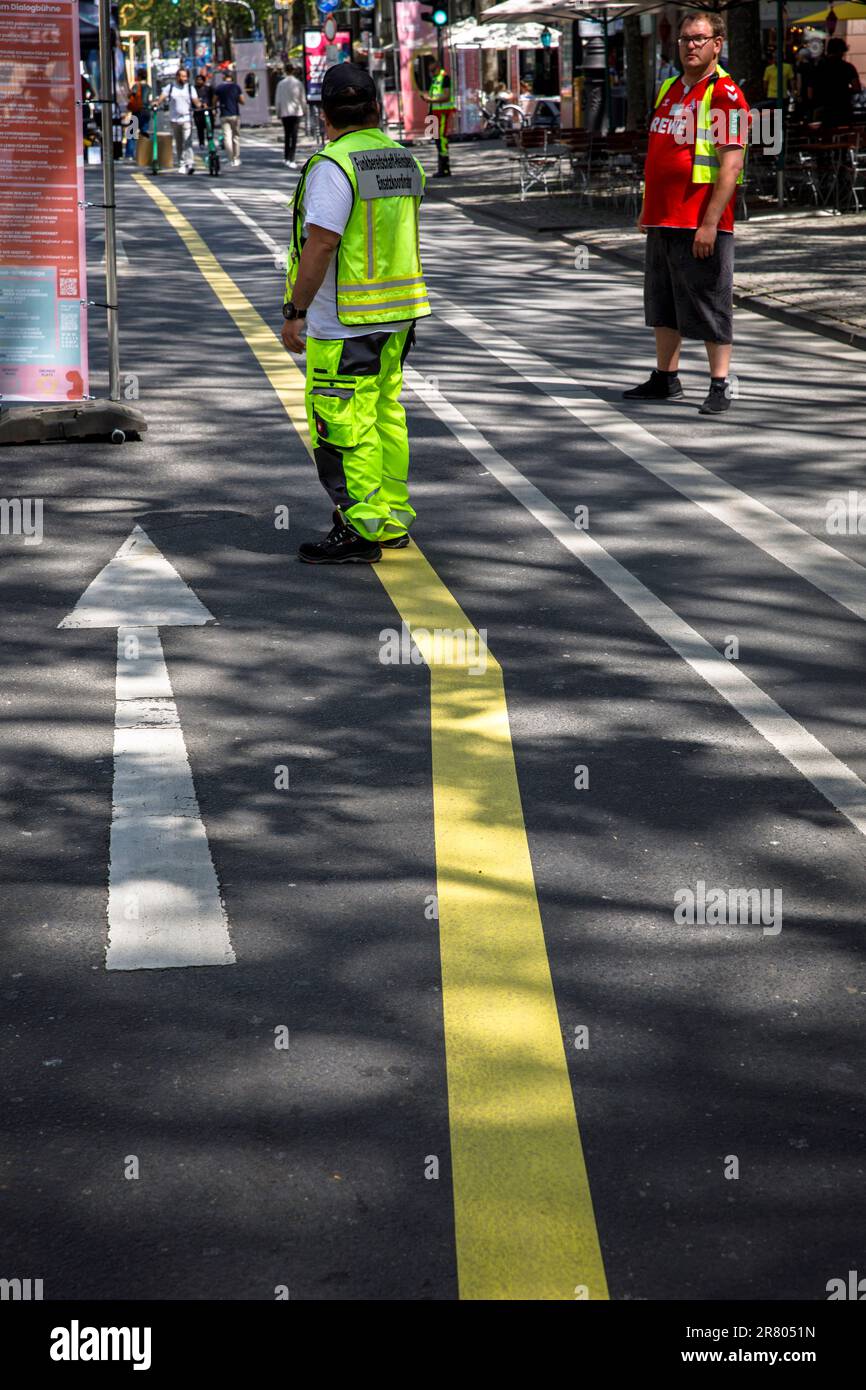a man in yellow protective clothing stands on a yellow road marking on Hohenzollernring street, Cologne, Germany. ein Mann in gelber Schutzkleidung st Stock Photo