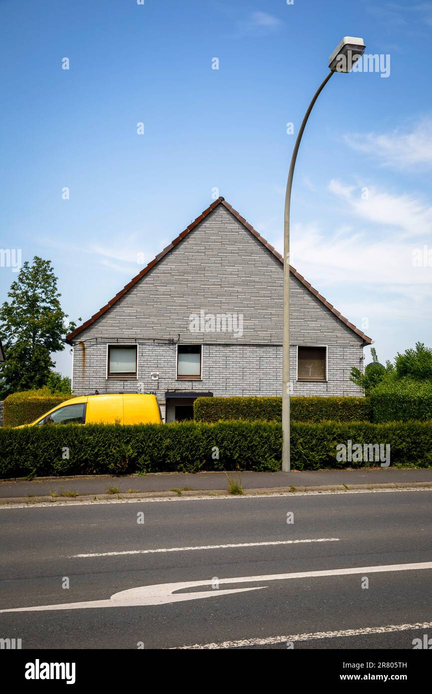 a yellow car stands behind a hedge in front of a gray brick house in Gevelsberg-Silschede, North Rhine-Westphalia, Germany. ein gelbes Auto steht hint Stock Photo