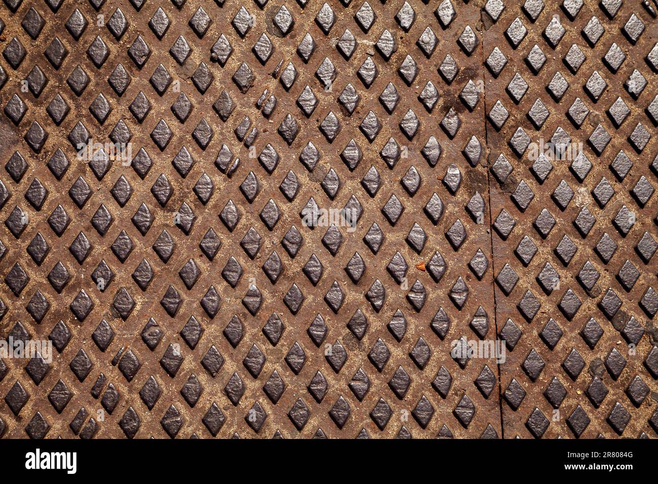 Rusty worn out tread plate with a diamond pattern used for slip resistance. Old metal sheet with a rhombus pattern, industrial background - Stock Image