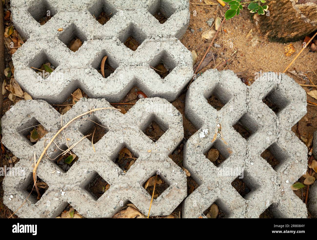 Turfstone pavers with holes for grass at a construction site, ready for installment. Lattice-grid concrete paving blocks lying on the ground - Stock Image