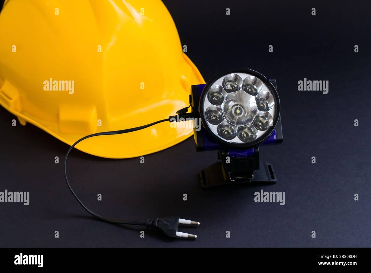 Yellow color worker's hard hat,helmet on black background with rechargeable overhead light Stock Photo