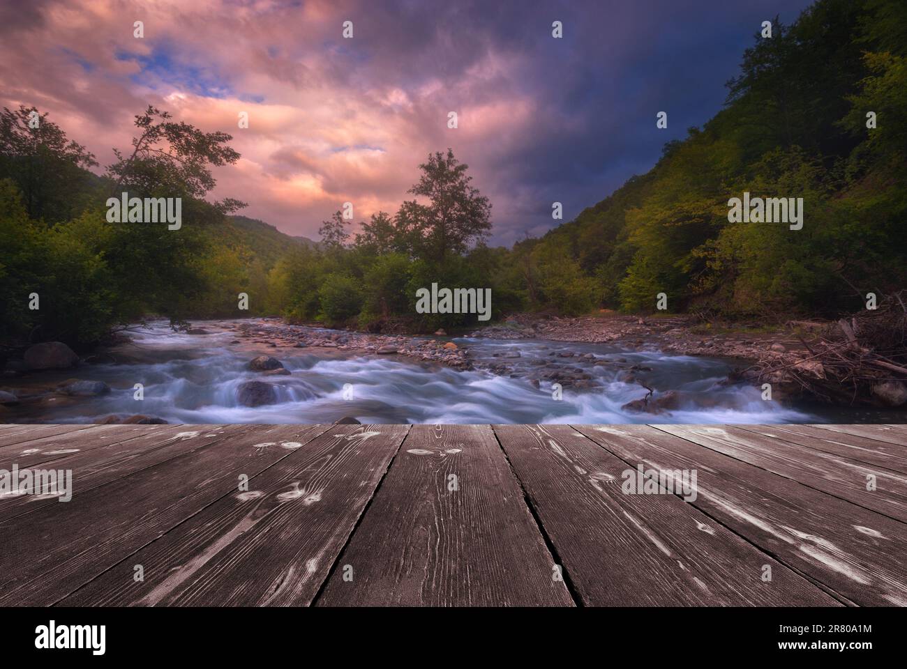 Fast mountain river flowing with empty wooden batten bridge. Natural ...