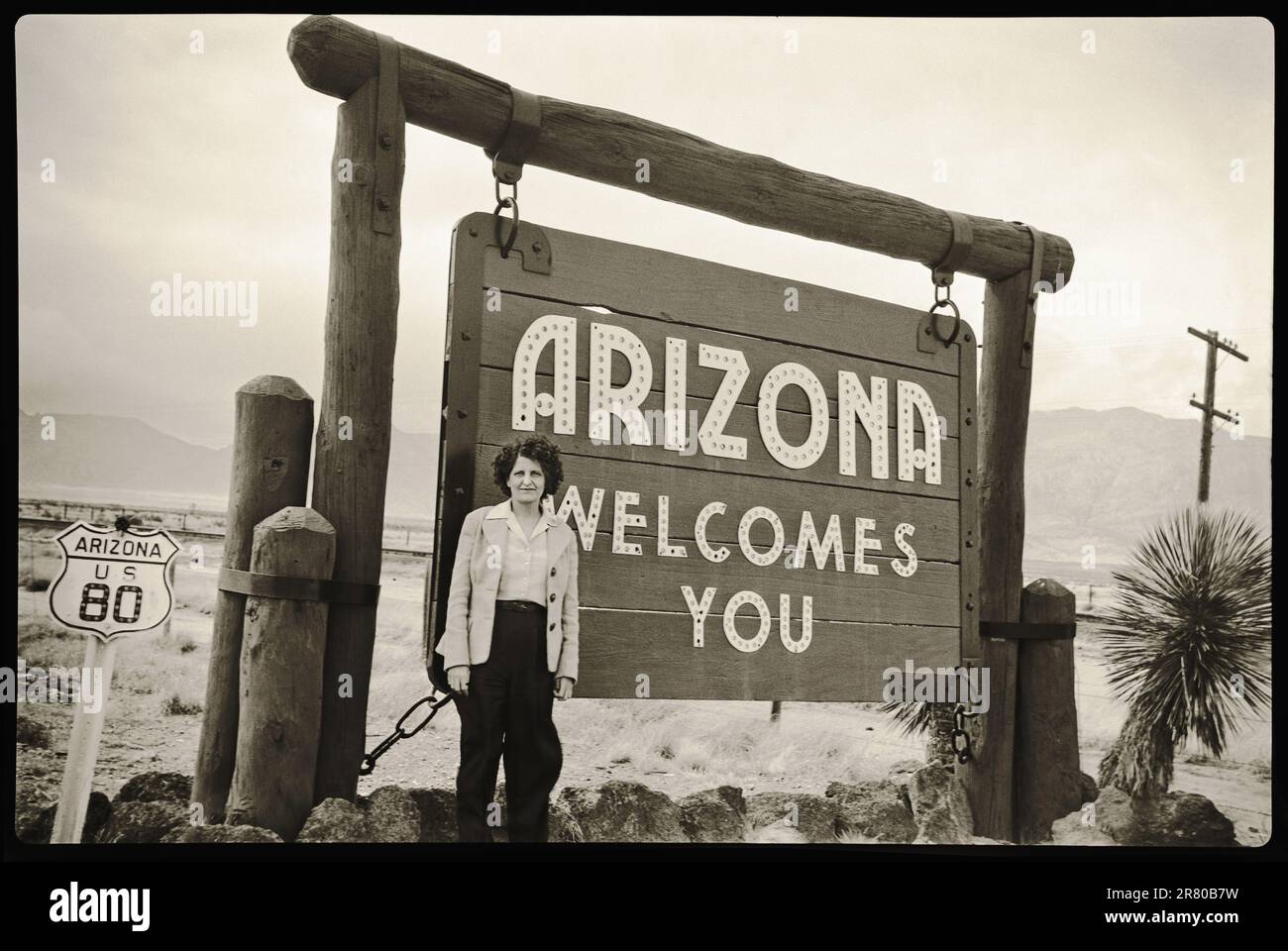 Arizona State Sign 1960s. Woman standing by Arizona sign along State Highway 80. Image from 6x9cm B&W negative. Stock Photo