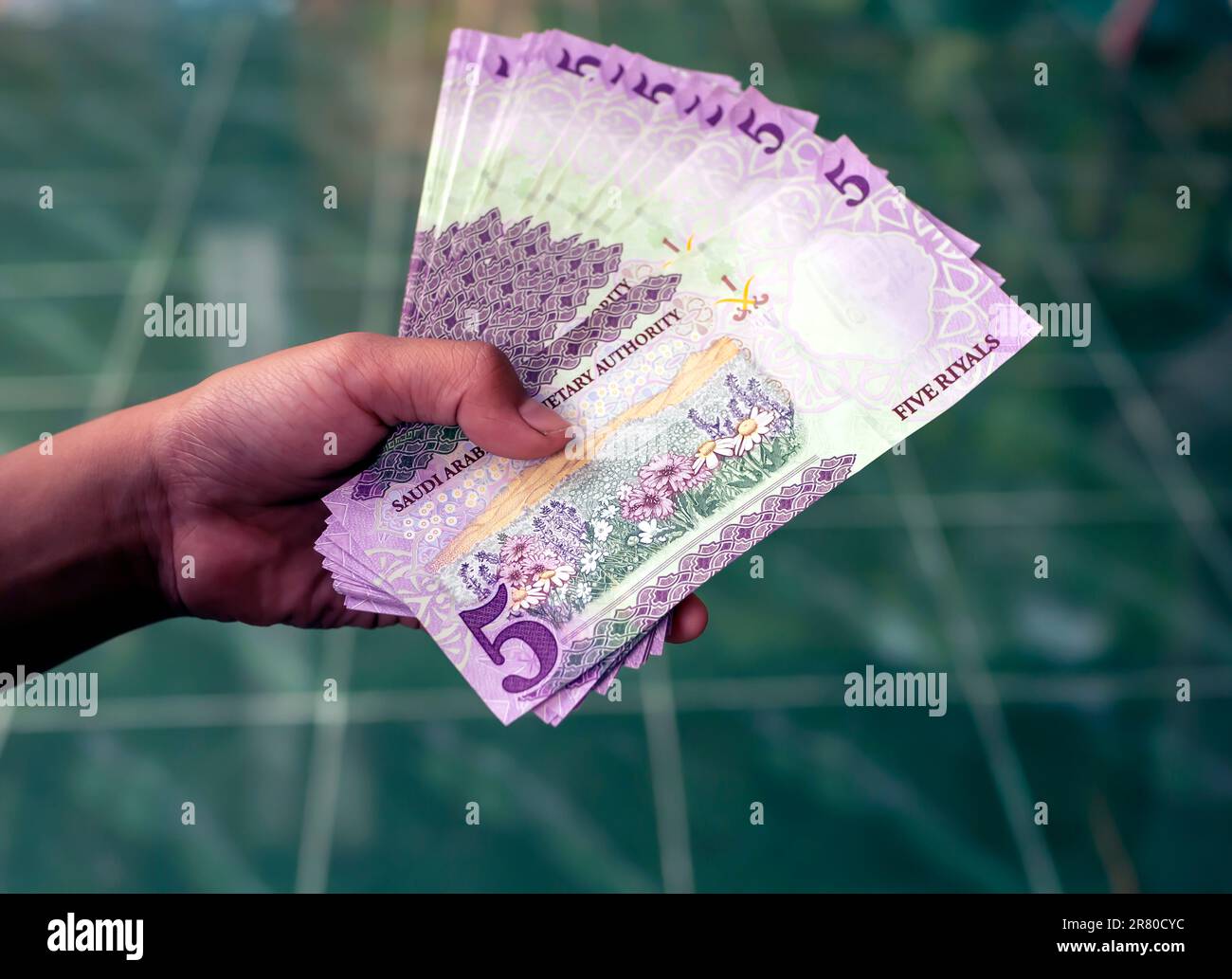 Asian children hand with five Riyal, the currency of Saudi Arabia, concept of giving and charity Stock Photo