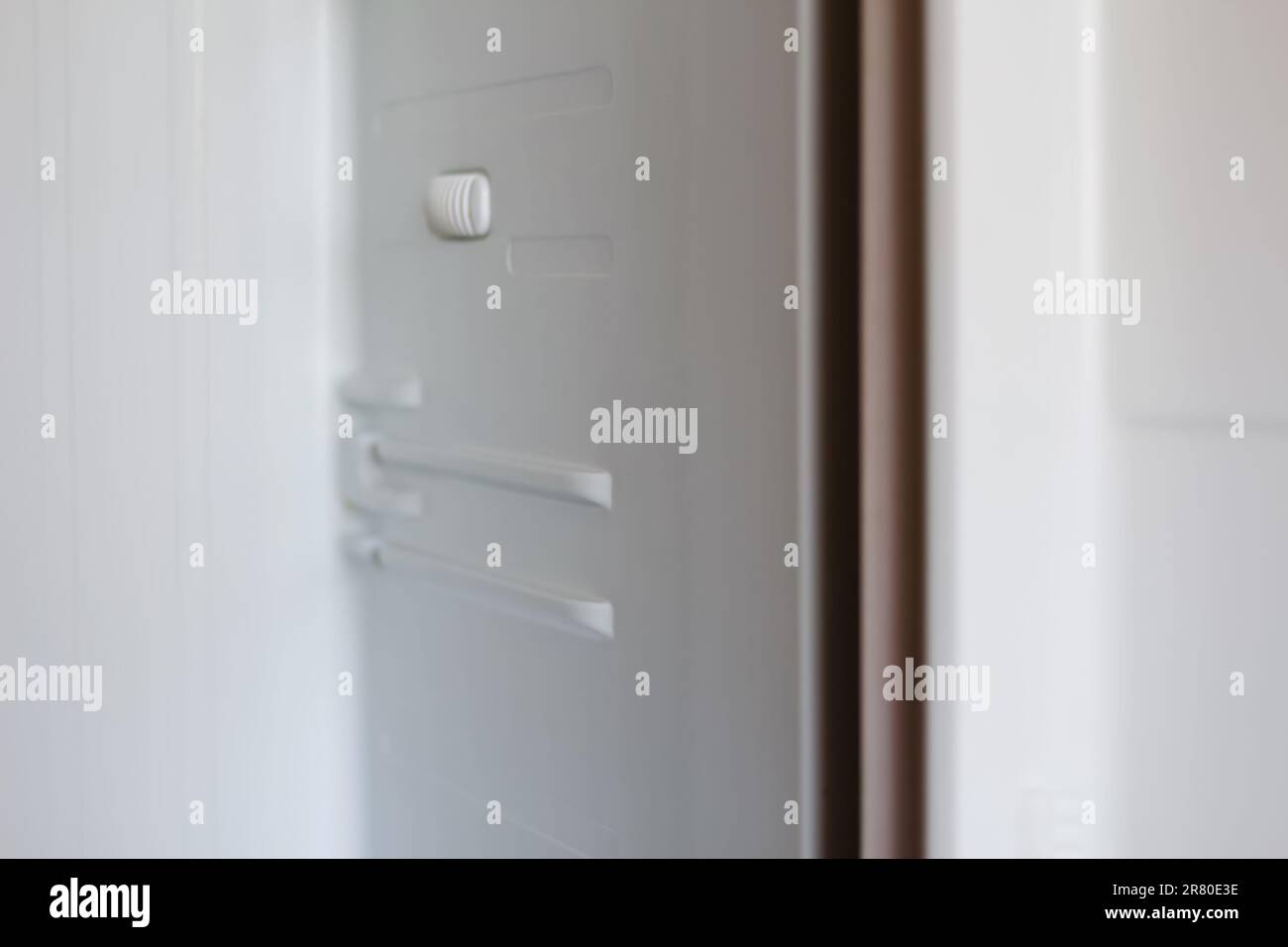 An empty white refrigerator with open doors reveals its shelves, showcasing its spacious interior. Out of focus Stock Photo