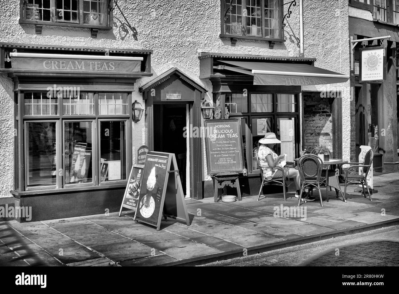 Woman alone outdoor at a pavement cafe - England UK. Black and white photography Stock Photo