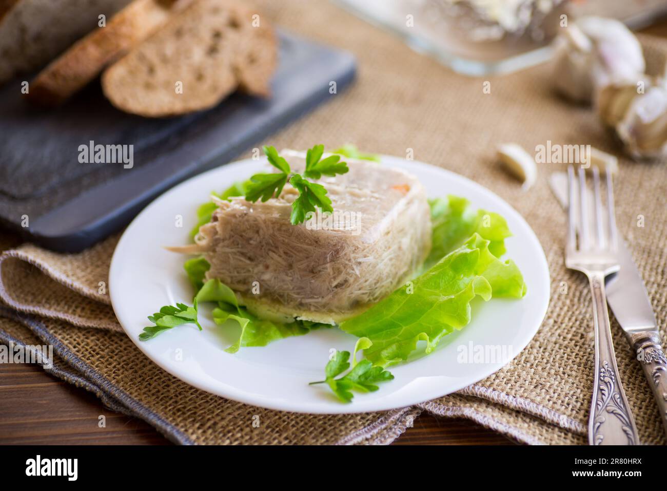 Boiled chicken meat aspic in meat gelatin broth in a plate Stock Photo