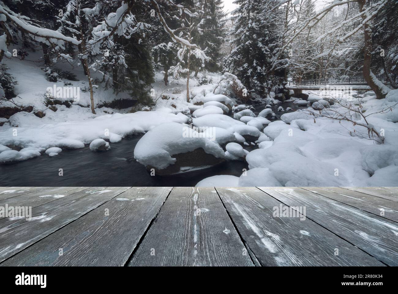 River flowing through a forest in winter with empty wooden batten ...