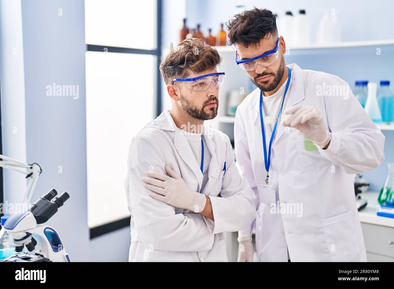 Young couple wearing scientist uniform holding sample at laboratory