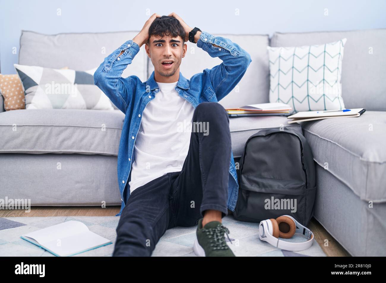 Scared While Study Young hispanic man sitting on the floor studying for university crazy ...