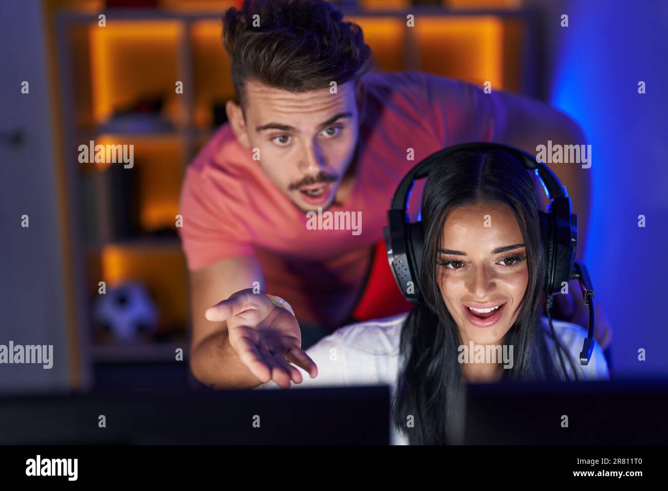 Man and woman streamers playing video game using computer at gaming ...