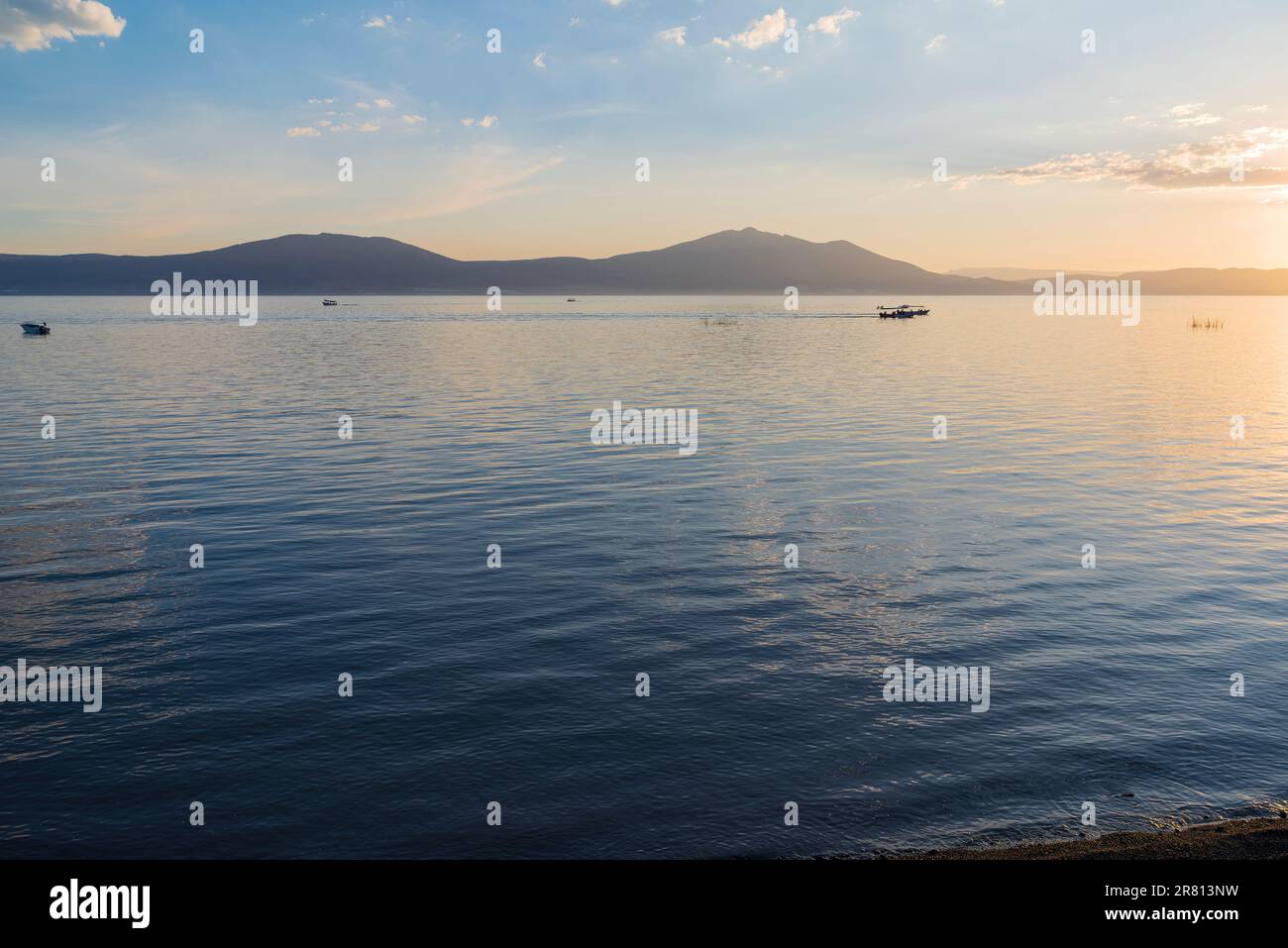 boats on lake chapala as sun sets and mountains along horizon viewed