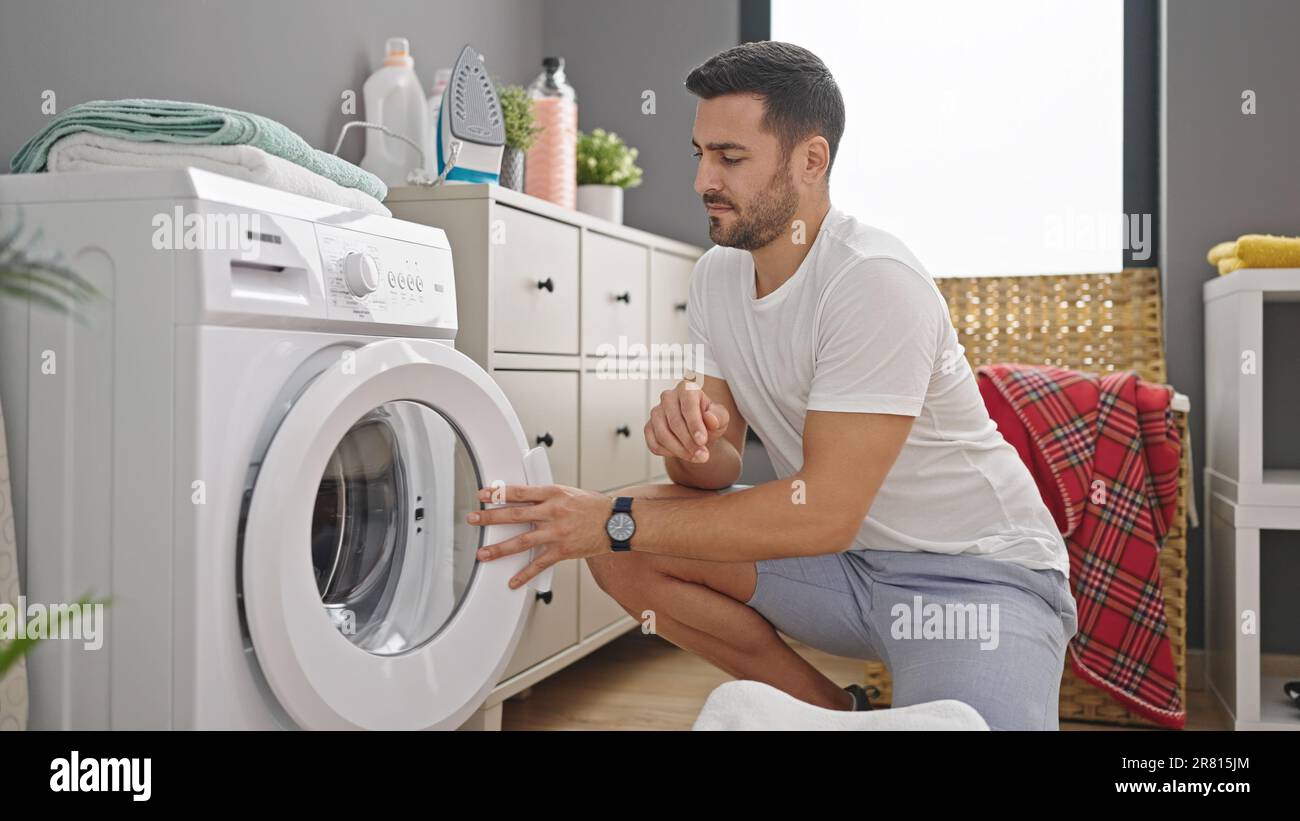 Young hispanic man doing laundry at laundry room Stock Photo