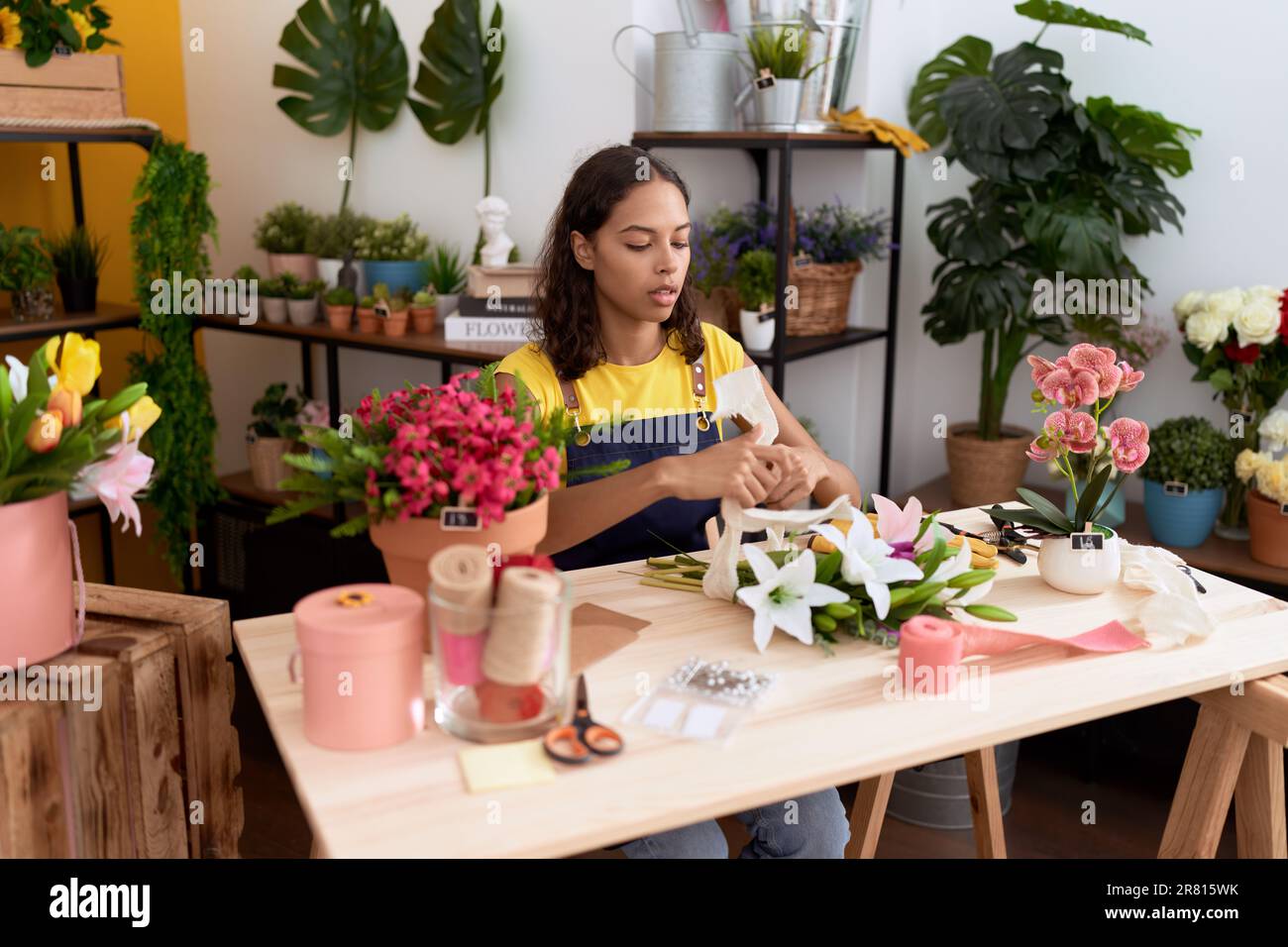 Young african american woman florist make bouquet of flowers at flower ...