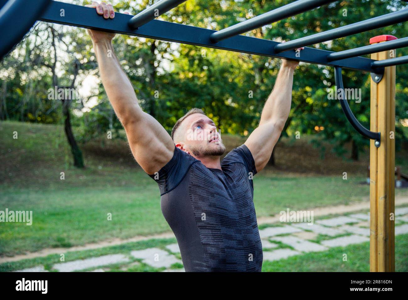 A fit man trains in an outdoor park with bars, outdoor workout Stock Photo