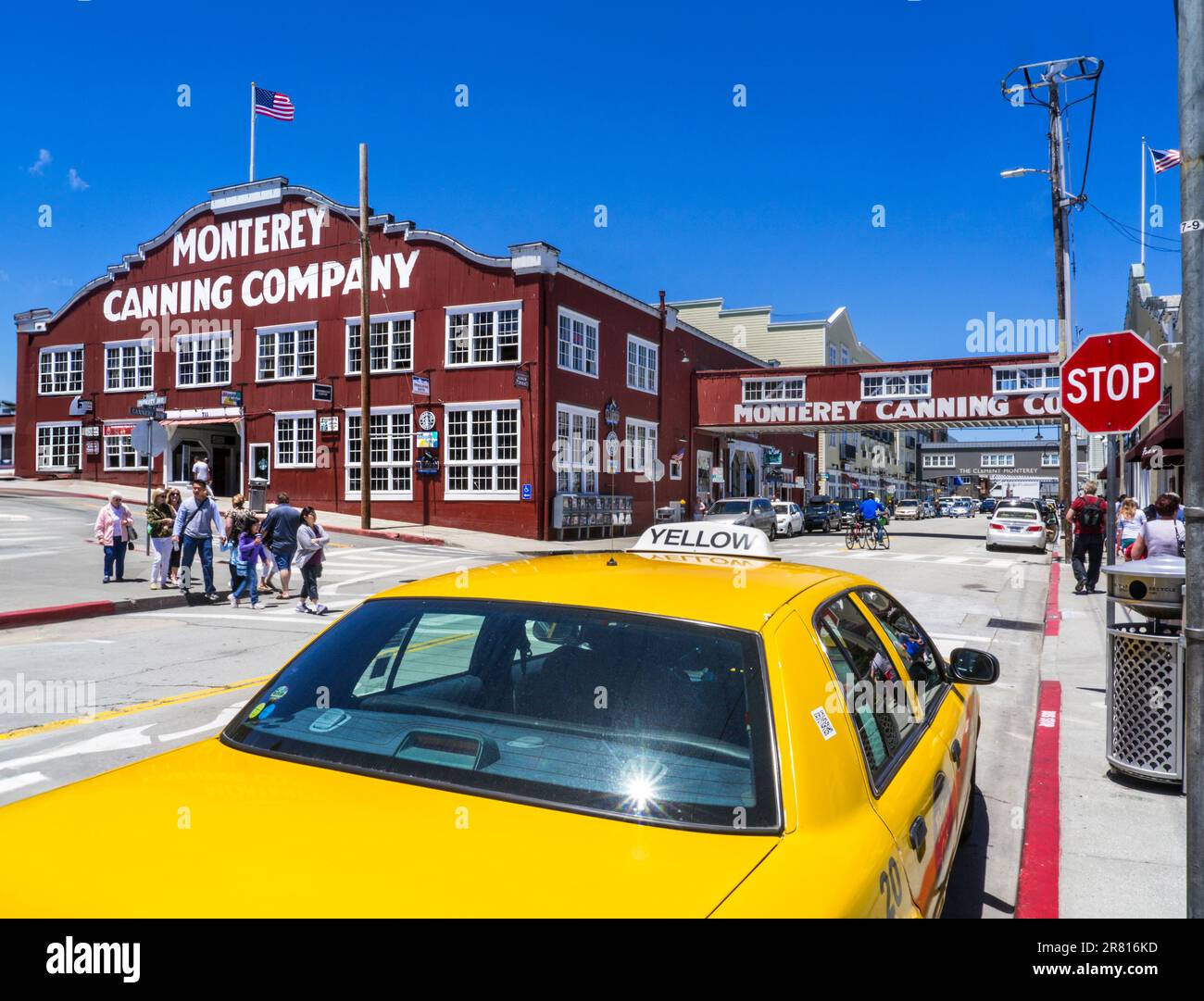 MONTEREY CANNERY ROW Canning Company building with iconic yellow taxi cab in foreground and Stop road sign. Americana. Monterey California USA Stock Photo