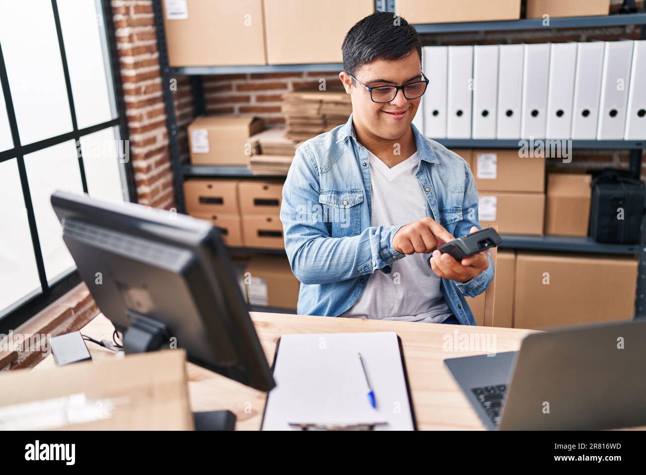 Down syndrome man ecommerce business worker using data phone at office Stock Photo