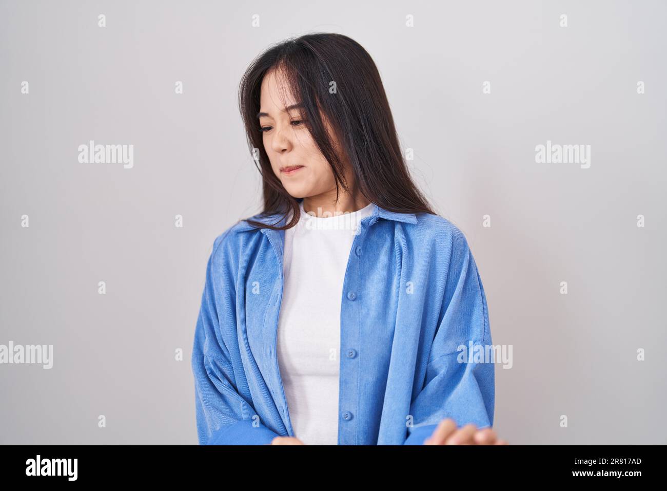 Young chinese woman standing over white background disgusted expression, displeased and fearful doing disgust face because aversion reaction. Stock Photo