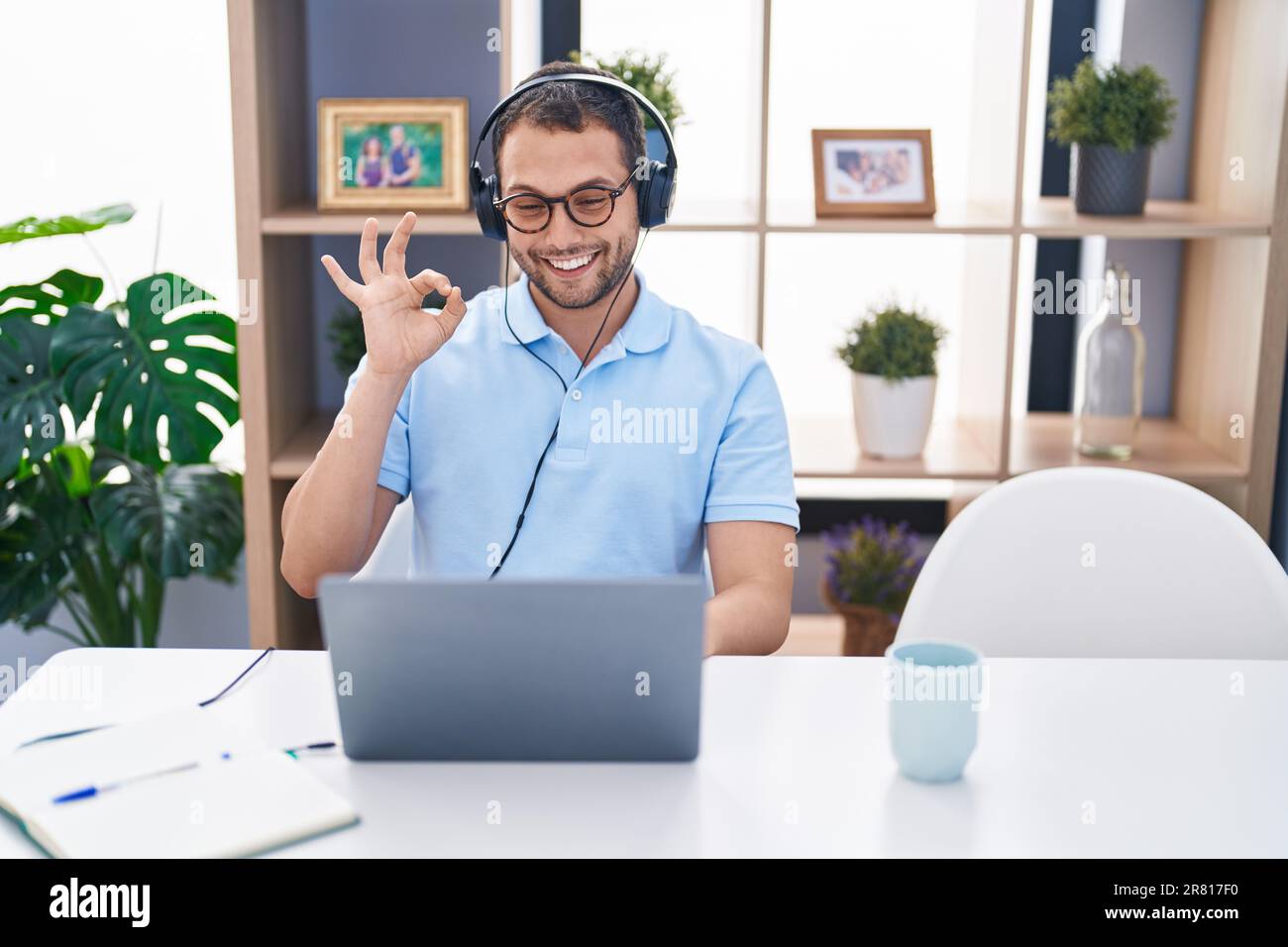 Hispanic Man Using Computer Hispanic man working using computer laptop wearing headphones doing ok ...