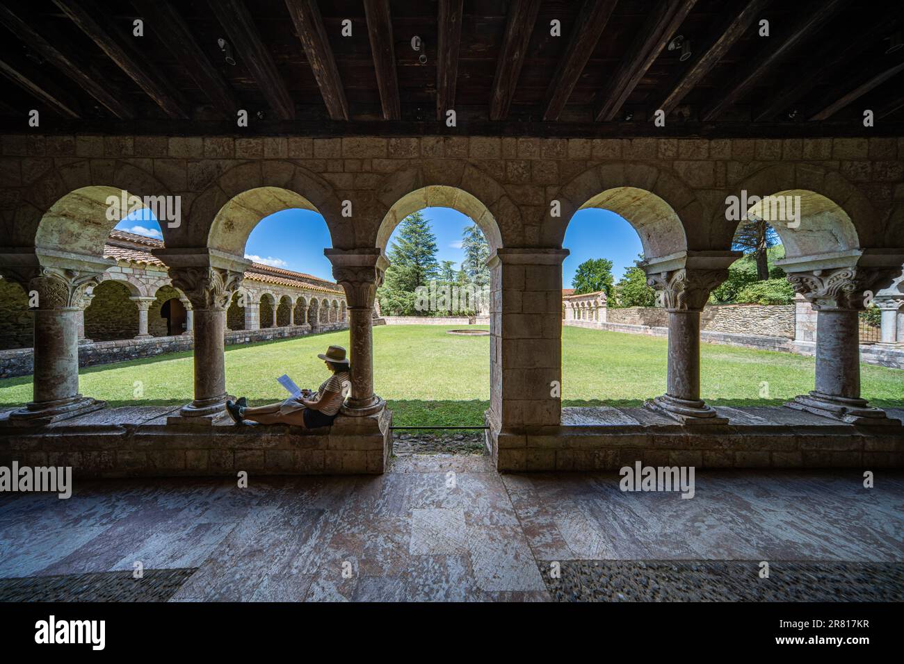 A woman reading in the cloister of the Abbey of Saint-Michel de Cuxa, France Stock Photo