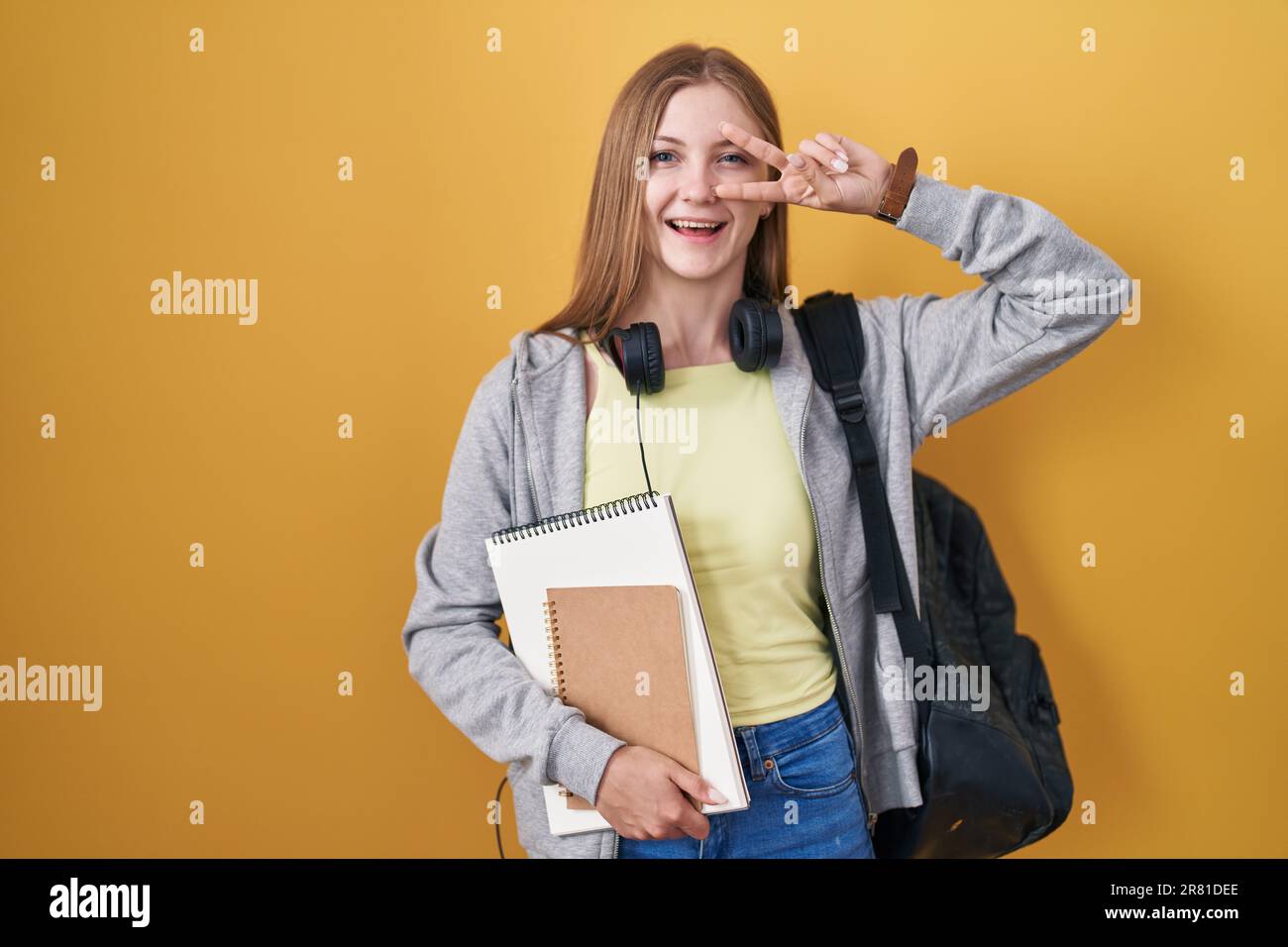 Young caucasian woman wearing student backpack and holding books doing ...