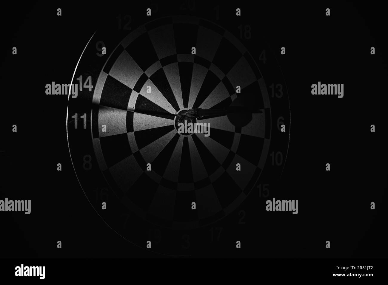 Darts in the dark and a beam of light in the center close up, black and white photo Stock Photo