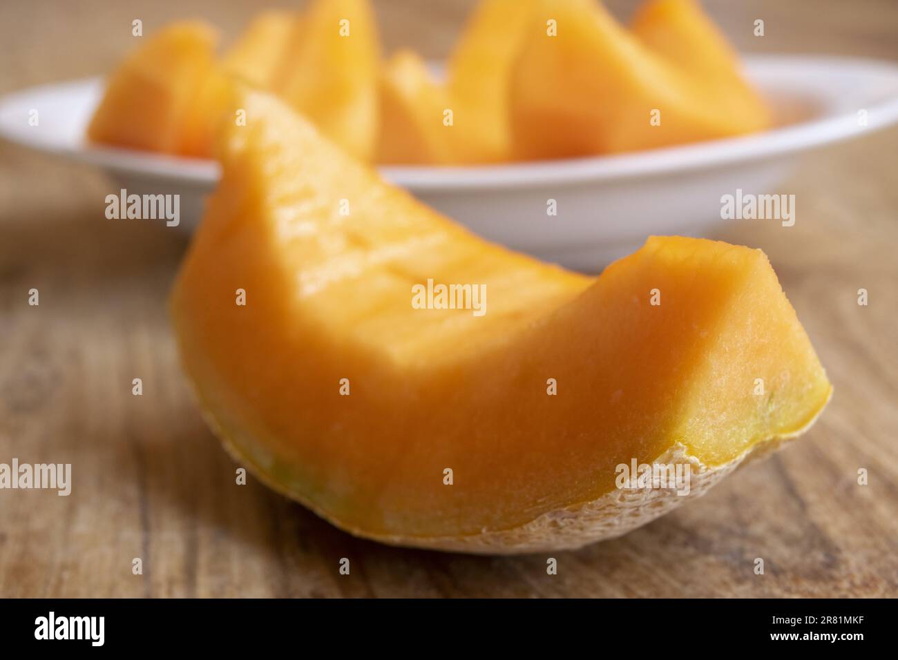 slice of cantaloupe melon with a plate full of slices of the same fruit