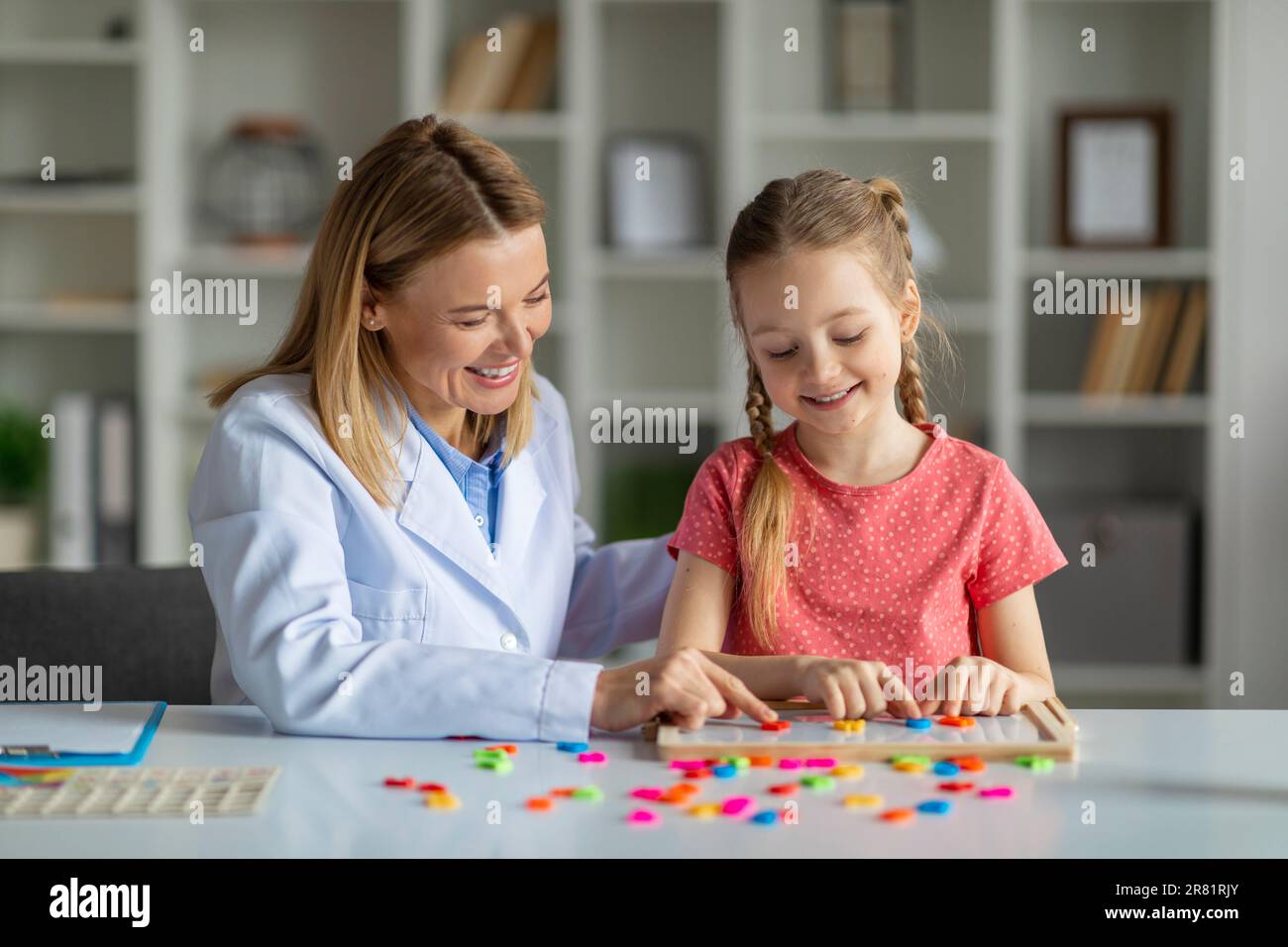 Child development specialist lady working with cute little girl Stock