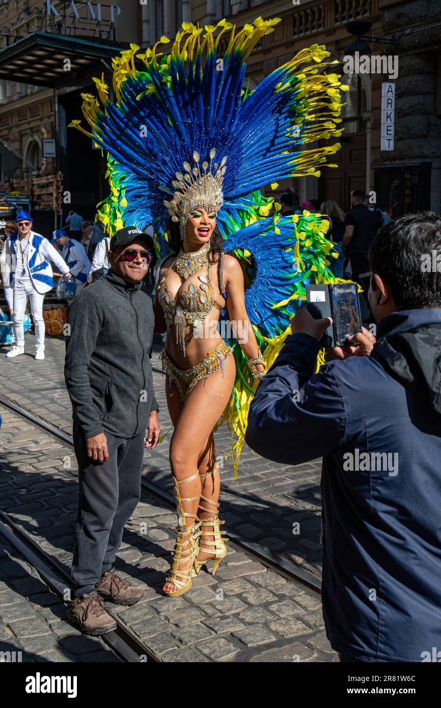Female samba dancer in carnival dress posing with male spectator at Aleksanterinkatu after Helsinki Samba Carnival in Helsinki, Finland Stock Photo