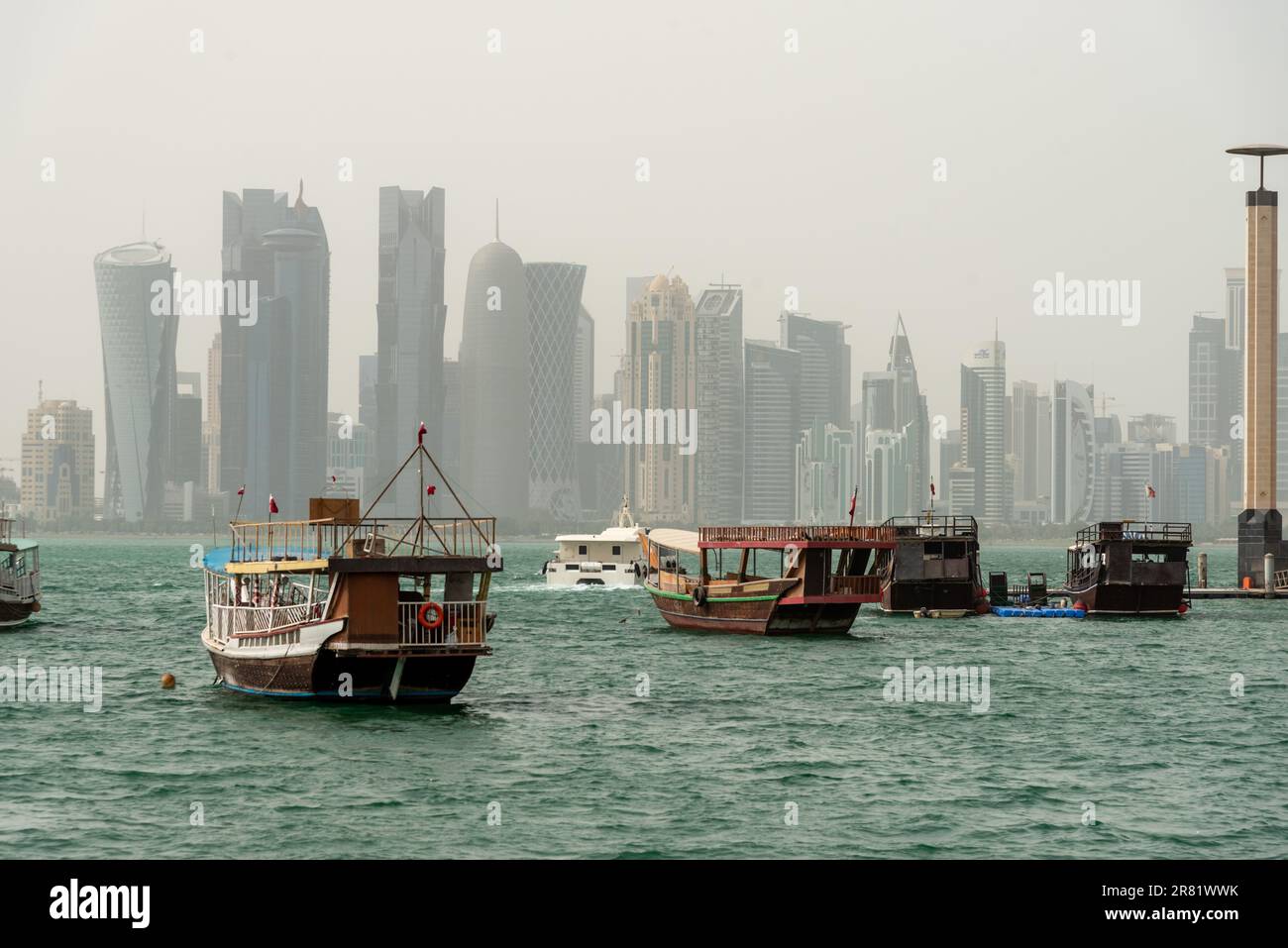 Traditional dhow pearl fishing boat at The Corniche with skyscrapers misty view in the background , Doha, Qatar Stock Photo