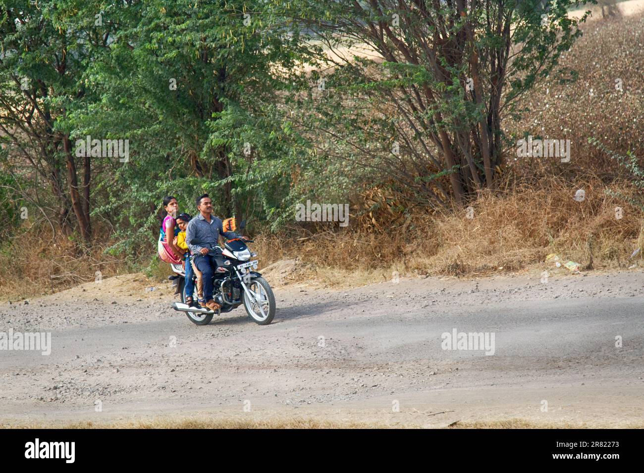 India, Pune - April 6, 2018: Young Indian family with a child on a motorcycle. Woman is sitting sideways, not astride Stock Photo