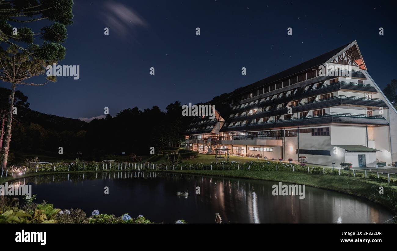 A vibrant areal shot of a hotel with a pool outside illuminated in the night Stock Photo