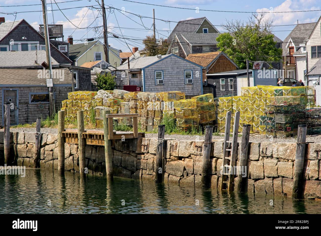 Stack of lobster traps stand on granite stone wall of Bradley wharf