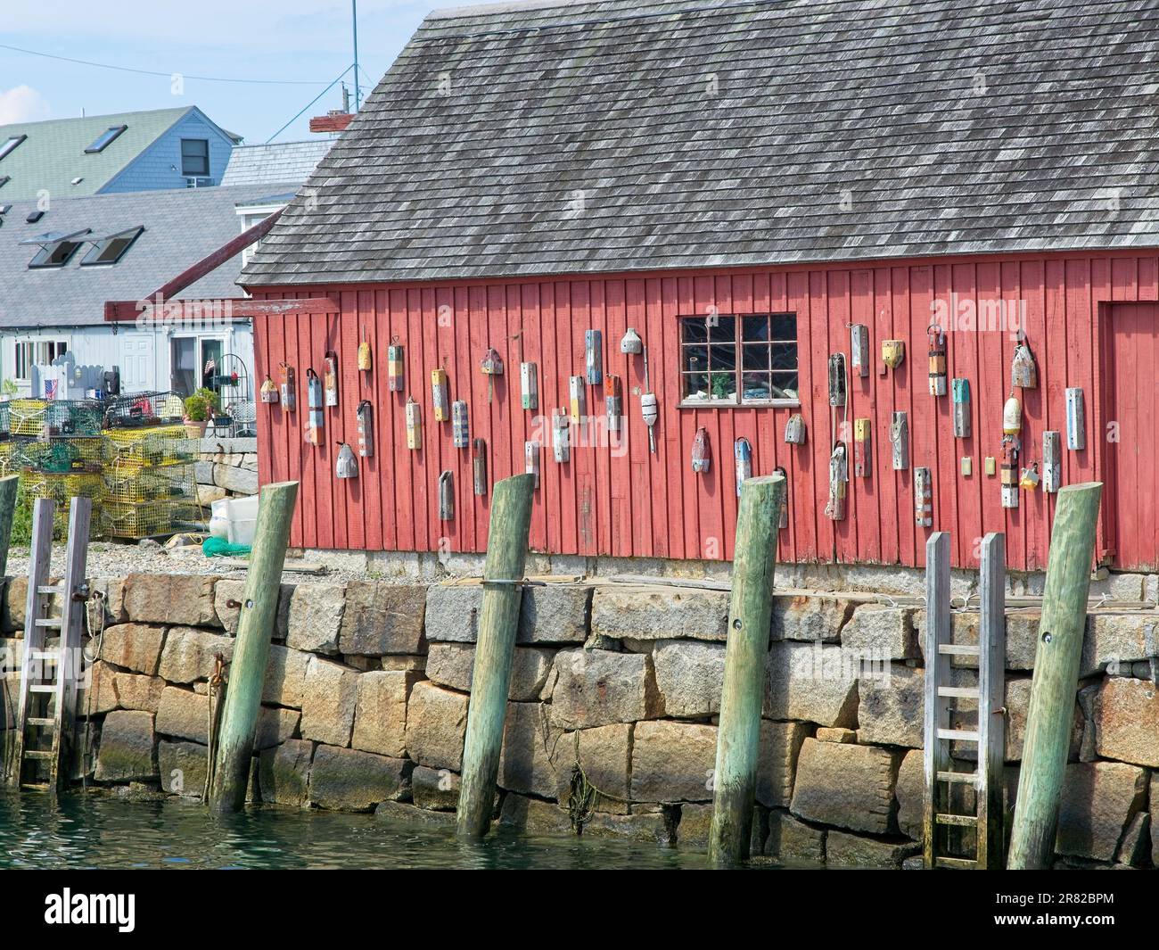 Mooring buoys hang on red board and batten wall of landmark Motif Number One fishing shack on Bradley Wharf in Rockport Massachusetts Stock Photo